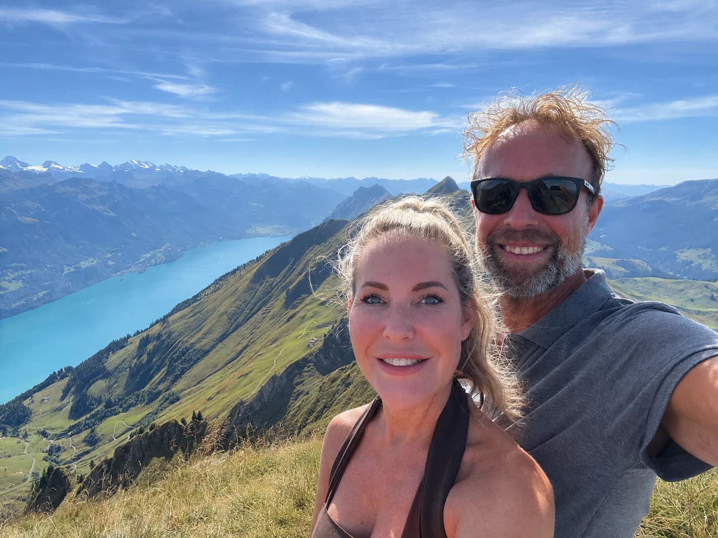 Karin en haar partner op een bergtop in de Zwitserse Alpen, met uitzicht over het meer